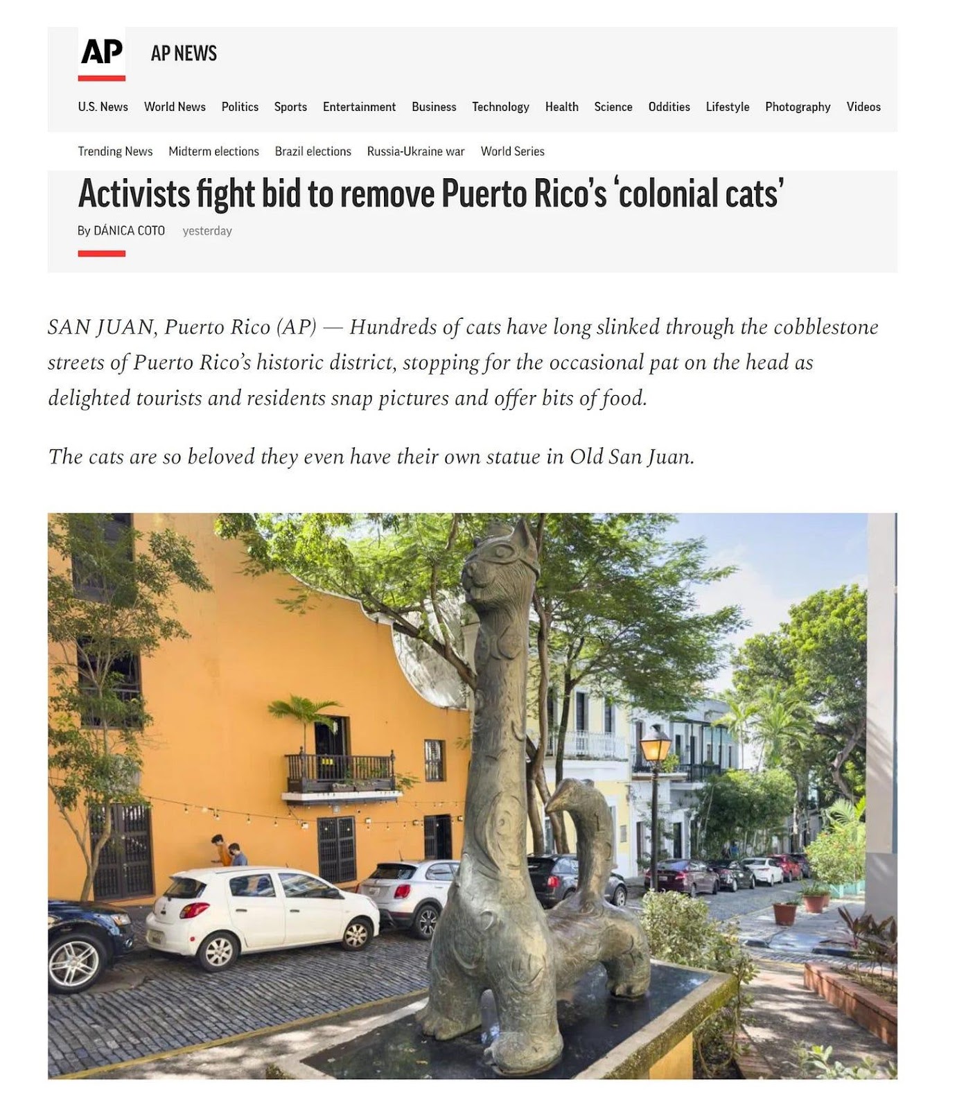 A statue of a cat on a street

Description automatically generated